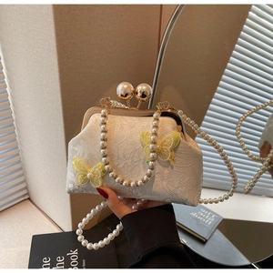 Détail du sac jacquard en dentelle crème avec papillon et bandoulière en perles