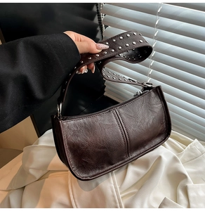 Detail of dark brown faux leather shoulder bag featuring silver metal studs on wide strap