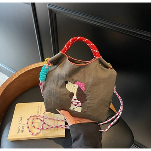 Detail of canvas dachshund bag with dog embroidery and colorful braided rope handles