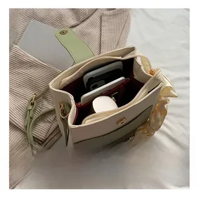 Interior view of the cream and green handbag showing spacious red lining and compartments