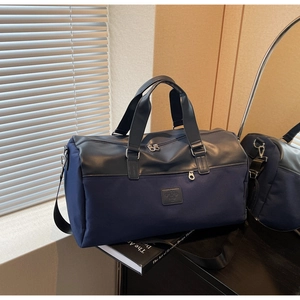 Detail of navy canvas travel bag with leather stitching and adjustable strap