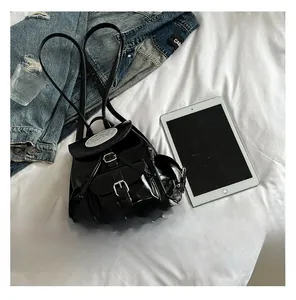 Close-up of black patent leather backpack with silver buckles and flap closure detail