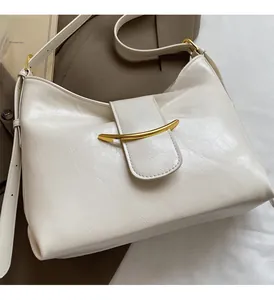 Détail de la boucle dorée brillante en forme de croissant sur un sac blanc crème