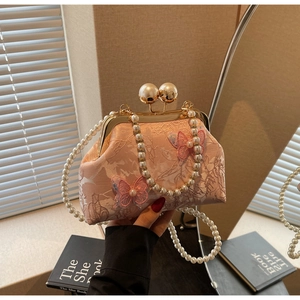 Détail de la pochette rose brodée papillon avec poignée en perles et fermoir doré
