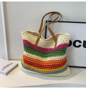 Detailed close-up of handmade woven rainbow gradient straw tote bag with brown handles