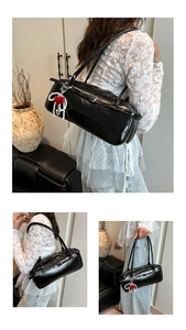 Detail of glossy black Boston bag with chic red heart and pearl charm accessory