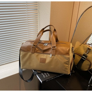 Detail of khaki canvas travel bag with brown leather handles and adjustable black strap