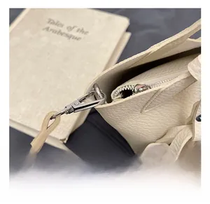 Detail of cream bucket bag showing lychee grain texture and silver metal swivel hook
