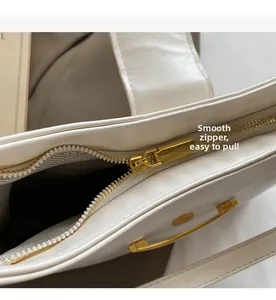 Vue détaillée de la fermeture éclair dorée et doublure texturée du sac cabas blanc