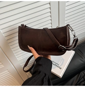 Close-up of a dark brown retro shoulder bag with smooth texture and silver zipper detail