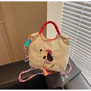 Detail of dachshund embroidery on beige canvas bag with colorful braided straps