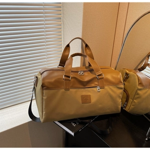 Detail of travel tote showing brown leather trim and khaki fabric with brand logo