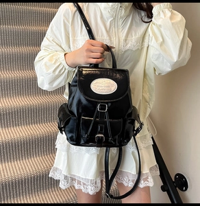 Detail of black glossy backpack with Moon Shark label and adjustable straps