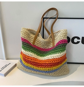 Detailed close-up of rainbow striped woven straw tote bag with brown faux leather handles