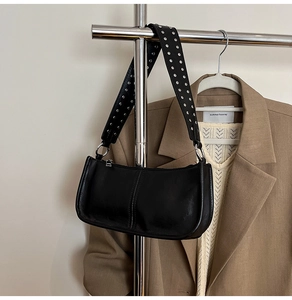 Detail of black faux leather bag with wide strap featuring double rows of silver rivets