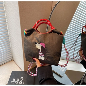 Detailed embroidery of a cartoon dog on a brown handbag with colorful woven straps