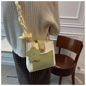 Detail of a chic bicolor mini crossbody bag featuring a wooden button and floral charm detail