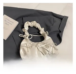 Détail de la poignée plissée crème et des nœuds décoratifs sur le sac demi-lune chic