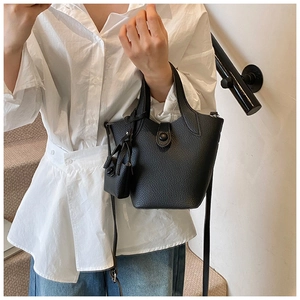 Detail of black lychee-grain bucket bag featuring mini charm and textured leather finish