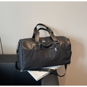 Close-up of a black leather and canvas travel tote bag with brand embossed logo detail