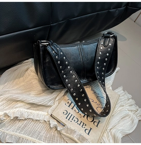 Detail of silver round rivets on a black leather vintage shoulder bag strap