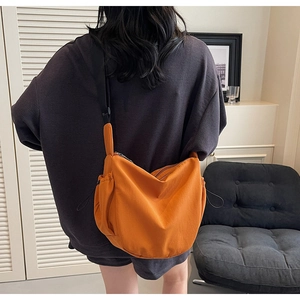 Bright orange nylon crescent crossbody bag with adjustable strap worn by model in casual style