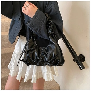 Détail du sac cabas en cuir noir avec nœuds décoratifs et bandoulière plissée