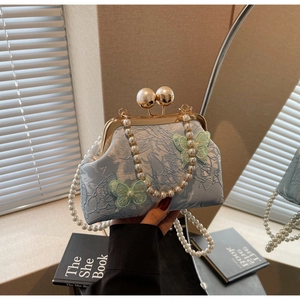 Détail du sac coquillage en jacquard bleu clair avec applique papillon et fermoir perle