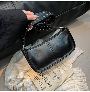 Detail of wide shoulder strap with silver metal studs on a black leather handbag