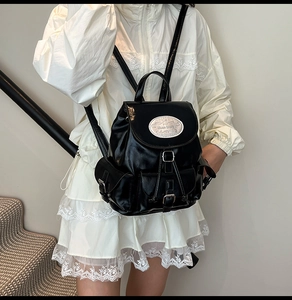 Detail of black leather backpack featuring shiny silver hardware and drawstring closure