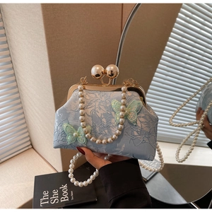 Détail du sac brodé papillon bleu clair avec fermoir perle et bandoulière