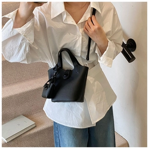Detail of black lychee grain leather bucket bag shown on model with shoulder strap