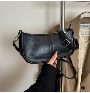 Detail of black textured faux leather handbag with silver zipper and stylish shoulder strap