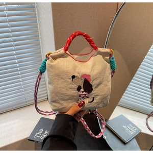 Detailed close-up of a canvas handbag with colorful dog embroidery and drawstring closure
