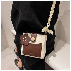 Detail view of mini contrast crossbody bag with braided strap and floral charm