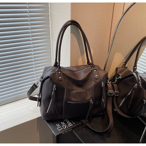 Detail of coffee brown pebble leather tote bag with functional zippers and tassels