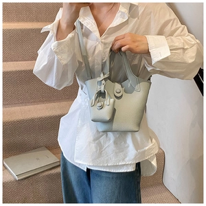 Detail of light blue lychee pattern bucket bag featuring a matching mini charm and strap