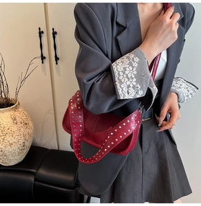 Detail of studded wide strap on burgundy crescent hobo shoulder bag for women