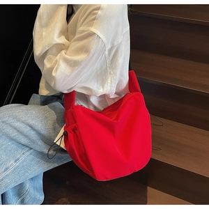 Detail of red crescent canvas bag showing adjustable side drawstrings and zipper closure