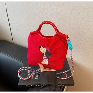 Macro detail of red canvas tote bag with cartoon dog embroidery and woven shoulder strap