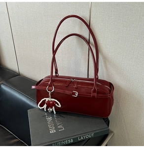 Detail of wine red cylinder underarm bag with silver hardware and pearl heart charm