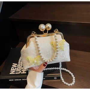 Détail du sac en dentelle blanche avec broderie papillon et poignée en perles