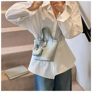 Detail of light blue bucket bag with pebble leather texture and mini matching pouch