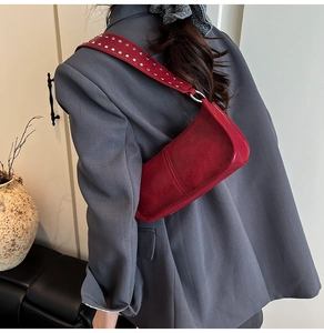 Detail of studded wide red shoulder strap on vintage crossbody bag with silver rivets