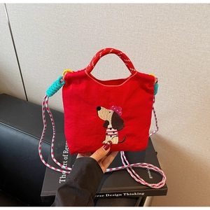 Detail of red canvas tote bag with cute dog embroidery and colorful woven shoulder strap