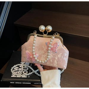Détail de la pochette en jacquard rose avec broderie papillon 3D et bandoulière en perles