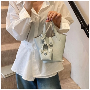 Detail view of light blue bucket bag with pebble leather texture and mini bag charm accessory