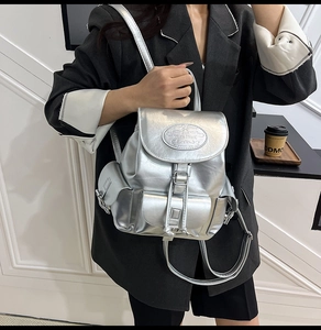 Detailed view of metallic silver backpack with drawstring and buckle closure on model