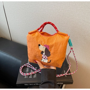 Detail of orange nylon bag with dog embroidery, colorful woven strap and knotted decor