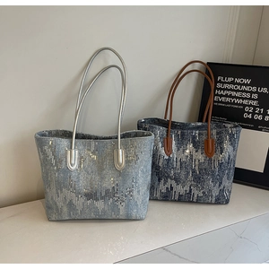 Detail shot of wavy silver sequin patterns on light and dark blue denim tote bags